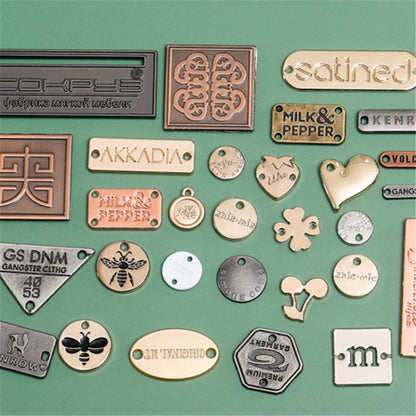 Assorted custom zinc alloy labels in multiple shapes and finishes